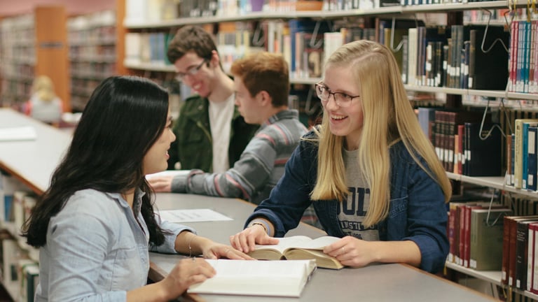 Students smiling and talking in the library.